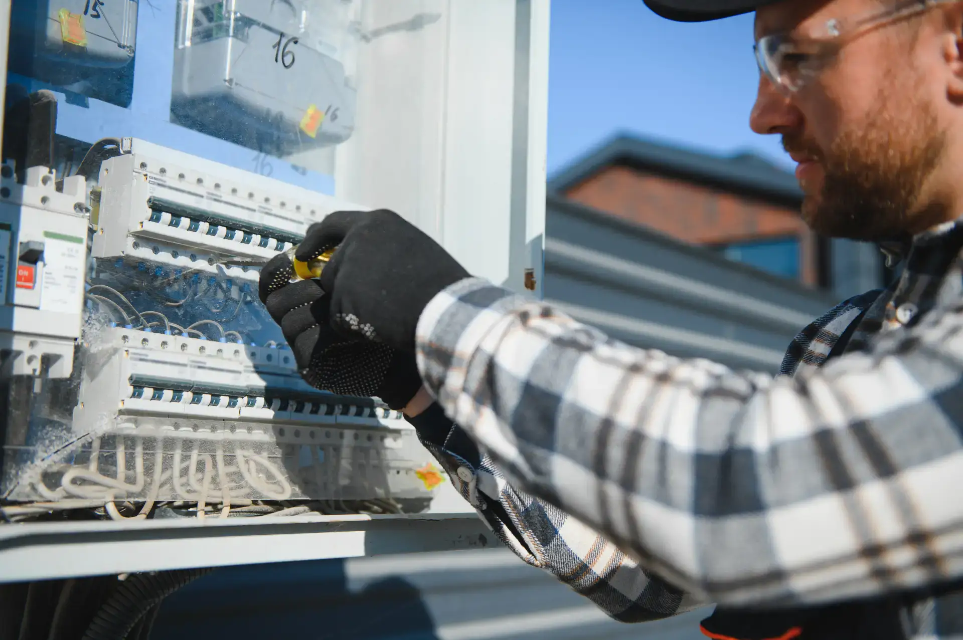 Elektriker arbejder på el-tavle med værktøj.